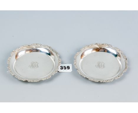 A pair of small sterling silver circular tray dishes by Tiffany having floral and scrolled borders, monogram centres, 4.5 ins