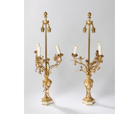 A pair of French gilt-bronze mounted white marble three light candelabra, of Louis XVI style, early 20th century, wired for e