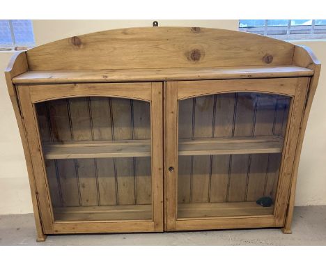 A modern pine 2 door wall hanging cabinet with interior and top shelf. Glass panelled doors, shaped back and sides. Complete 