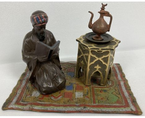 After Bergman - a cold painted Arabian style inkwell.  An Arabian gentleman knelt reading on a colourful carpet beside an ink