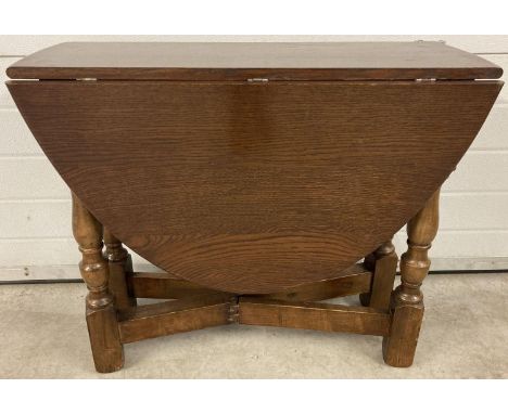 A chunky legged mid century oak drop leaf table with oval shaped top and gate leg supports. Approx. 68cm tall x 82cm long.  