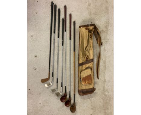 A vintage canvas and leather pencil golf club bag with a collection of vintage golf irons and woods. To include examples by W