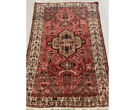 A vintage wool rug with red/brown ground and geometric design. Slightly stretched to one end. Approx. 200cm x 135cm (at wides
