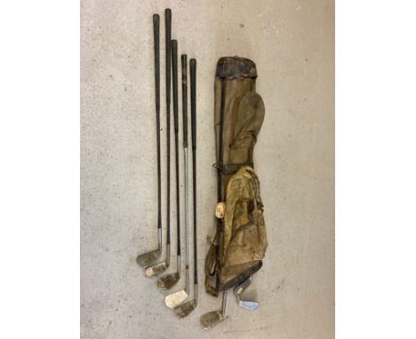A vintage canvas and leather pencil golf bag by Bryant together with 8 vintage golf clubs in varying conditions, mostly irons