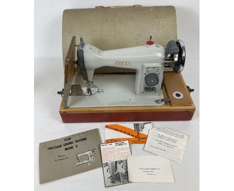 A vintage Jones electric hand sewing machine. Complete with manual, attachments, electric foot pedal and fold down side platf