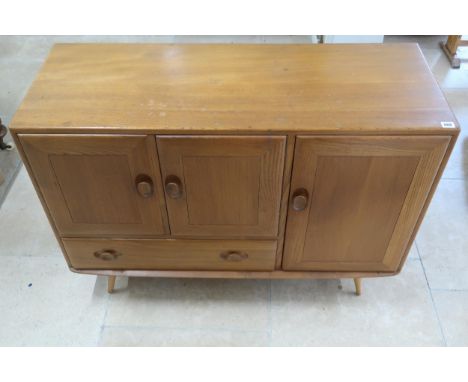 An Ercol blonde elm Windsor Centenary Cabinet of two doors over single drawer flanked by door raised on turned supports. 114c