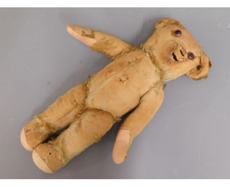 A 1930's Merrythought teddy bear with button ear, well loved with losses to fur