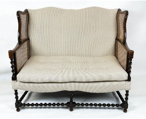 BERGERE WING SOFA, 99cm H x 117cm W, circa 1920, walnut, with  caned arms and ticking upholstery. 