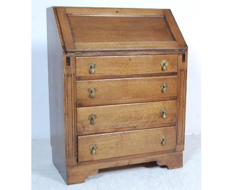 A vintage 1950s mid 20th century oak bureau having a fallfront writing area opening to reveal a fully appointed interior atop