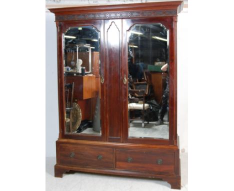 An early 20th century Edwardian mahogany double wardrobe. The wardrobe having twin bevelled glass mirror doors with scrolled 