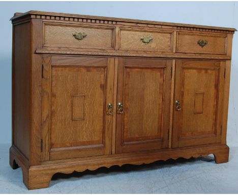 An early 20th century arts and crafts oak sideboard credenza having a raised back over a flared atop a run of three drawers w