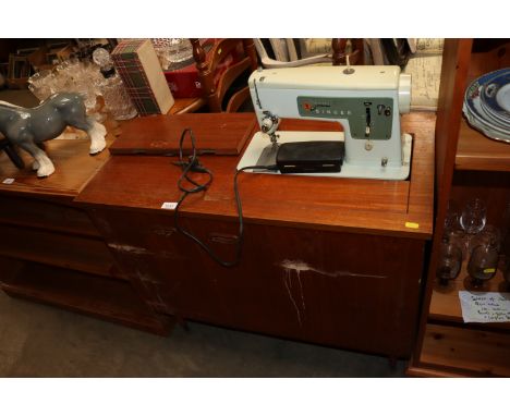 A Singer sewing machine with teak cabinet, sold as a collectors item