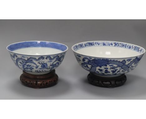 Two 19th century Chinese blue and white 'dragon' bowls, Kangxi mark, on wooden stands diameter 25.5cm