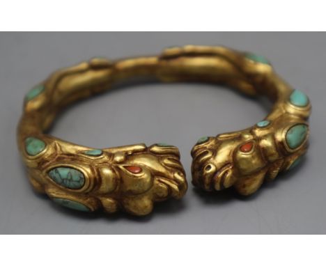 A Tibetan gilt metal and turquoise set open bangle.