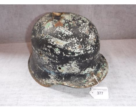 A GERMAN NAZI HELMET SHELL with layers of paint and war damage