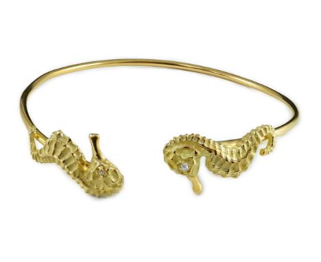 A modern gold and diamond chip set open work bangle, each terminal modelled as a seahorse with diamond chip eye, internal dia