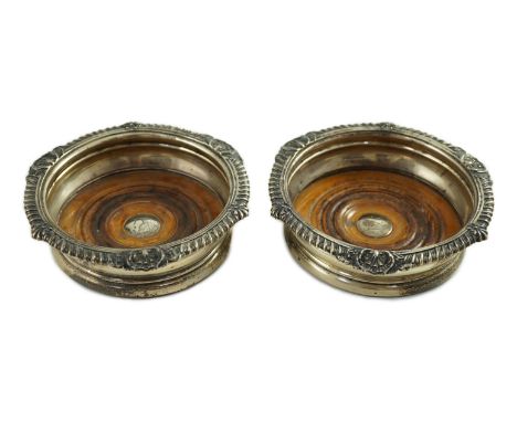 A pair of George IV silver mounted wine coasters by John Walton?, with gadrooned and scroll borders, turned wooden bases with