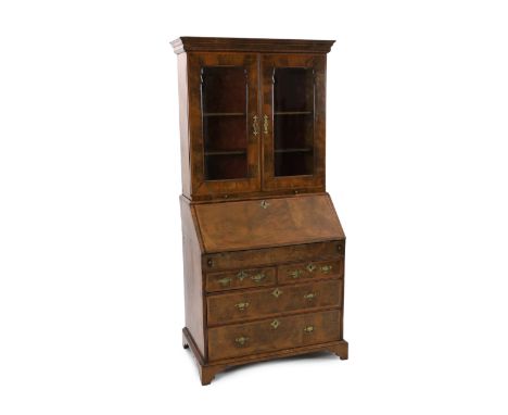 An early 18th century feather banded walnut bureau bookcase, with moulded cornice and two glazed doors, over two candle slide