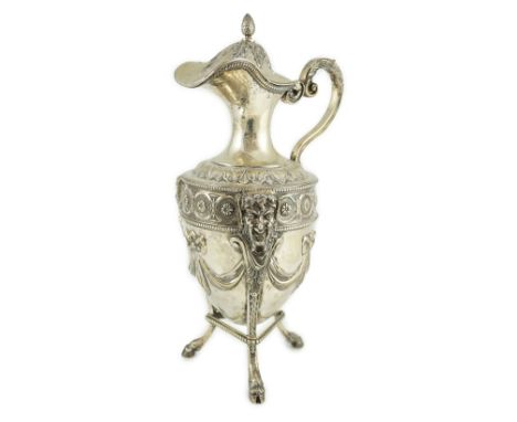 An 18th century French silver vase shaped claret jug, decorated with paterae and swags, on tripod supports with mask terminal