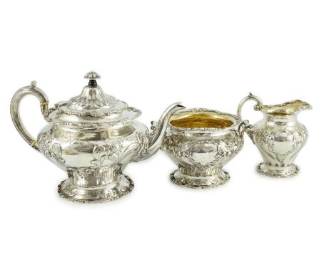 An Edwardian Scottish repousse silver three piece tea set, by Robert Scott, of inverted pear form and decorated with scrolls,