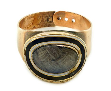 A George III gold and two colour enamel mourning ring, with adjustable 'buckle' shank, with plaited hair beneath a glazed pan