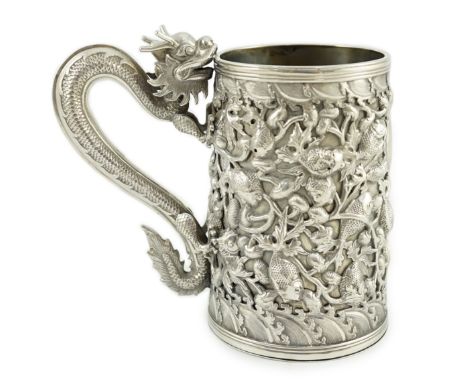 A late 19th century Chinese Export double skinned silver mug, by Cumwo, with dragon handle and embossed with shoal of fish, h