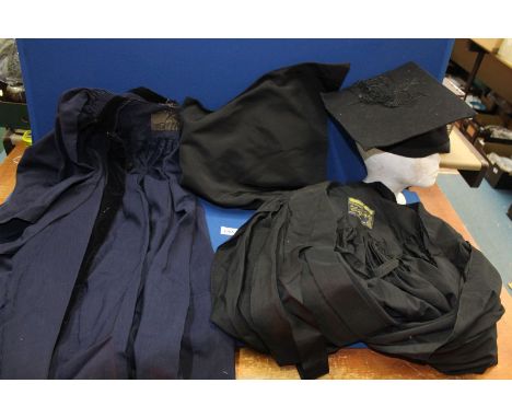 Two graduation gowns, one navy blue, the other black by Ryder & Amies, with a mortar board by W & G Taylor and a hood with wh