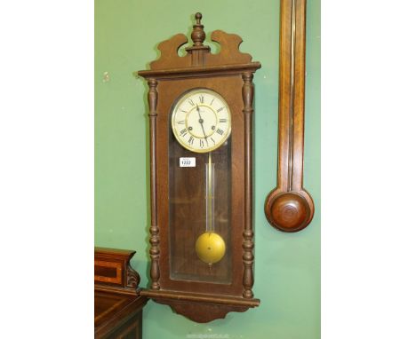 A dark-wood Hermle two-train movement Wall Clock striking the hours on a gong and having Arabic numerals. The pendulum and ke