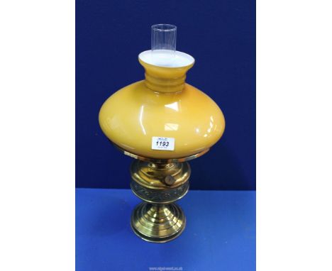 An Oil lamp having brass base with clear chimney and mustard colour glass shade, 19" tall.
