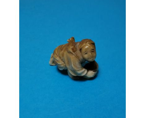 A Japanese Meiji peroid ivory Netsuke of a man cleaning a floor with a rat on his back 