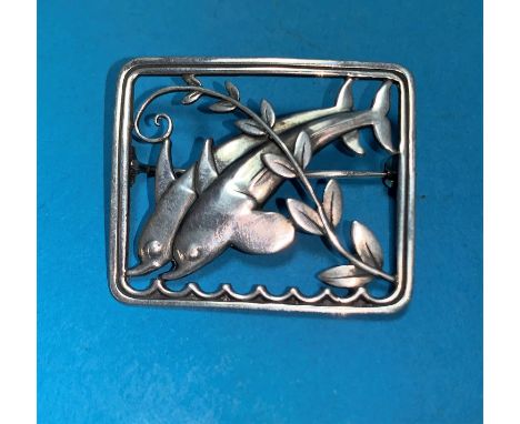A Danish sterling silver brooch designed by Arno Malinowski for Georg Jensen, with two leaping dolphins above waves and branc
