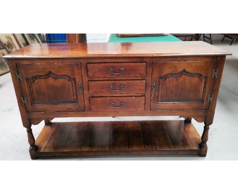 A Georgia style distressed oak dresser base in the style of Titchmarsh &amp; Godwin, having 3 central drawers, 2 arched and f