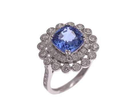 A SAPPHIRE AND DIAMOND CLUSTER RING Centrally set with a cushion cut... A SAPPHIRE AND DIAMOND CLUSTER RING Centrally set wit