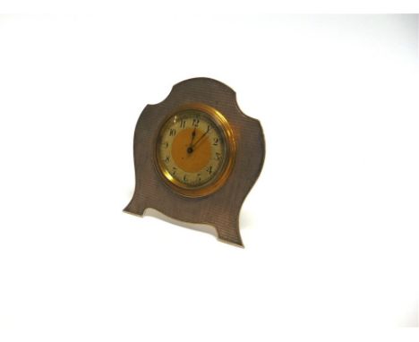 A SILVER MOUNTED 8 DAY BOUDOIR CLOCK by H. Matthews, Birmingham 1929, the engine turned shaped frame 8cm high, with brass eas