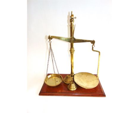 A SET OF W. & T. AVERY BRASS BALANCE SCALES set to a mahogany plinth base, 58.5cm high overall; together with two sets of bra