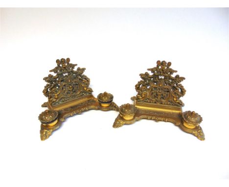 A PAIR OF CAST BRASS INKSTANDS in the rococo style, each with a letter rack and pen dish flanked by two lidded inkwells, 30cm