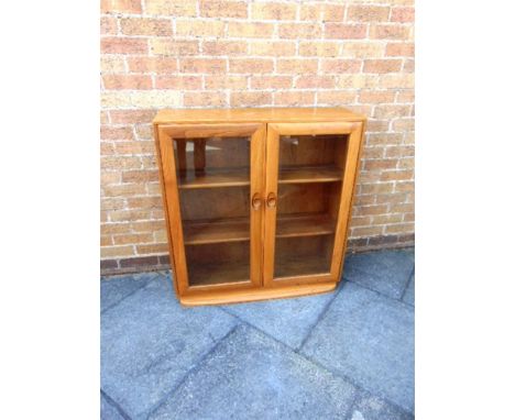 A ERCOL LIGHT ELM CABINET  with two bevel glazed doors opening to two adjustable shelves, 92cm wide 30cm deep 97cm high