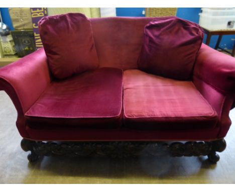 A Chippendale style oak framed three piece suite comprising a two seater sofa and two chairs, all having carved floral frieze