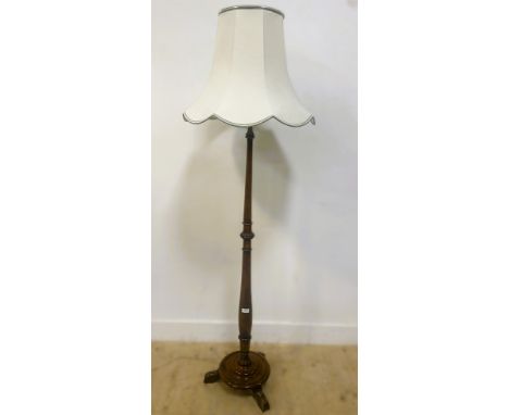 Mahogany standard lamp, raised on a circular base with three shaped feet, with a turned column and shaped white shade, 151cm 