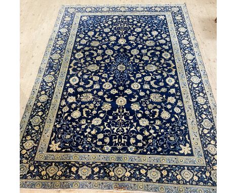 A large Kashan wool rug, with a navy ground with a central blue lozenge encased in a light blue floral border, 314cm x 230cm 