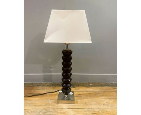 A Chelsom table lamp, raised on a square steel base with an amber coloured glass sectional body with a cream coloured satin e
