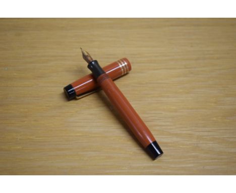 A Parker Duofold Junior button fill fountain pen in orange with three gold bands to the cap having Parker Duofold 14K Pen Can