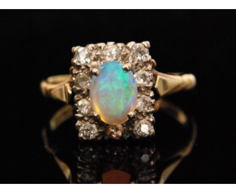 A 1970s 18ct opal and diamond dress ring, central oval shaped opal claw set above a rectangular diamond set border, weight 5.