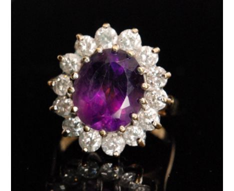 An 18ct hallmarked amethyst and diamond cluster ring, central oval  amethyst within a border of fourteen brilliant cut diamon