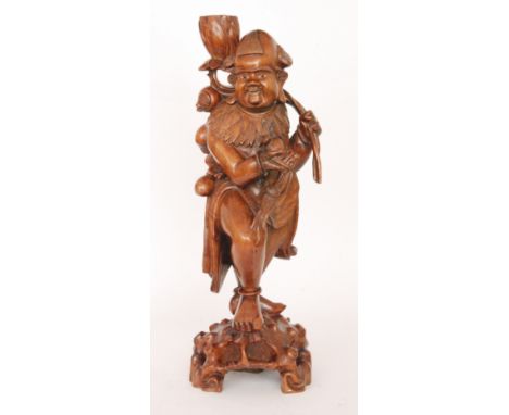 A carved Oriental hardwood lamp base in the form of a man holding a large lotus flower and a bough of peaches, height 59cm, S