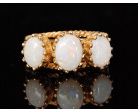 A modern 9ct opal three stone ring, high claw set oval opals to a pierced and rope twist effect head and shoulders, ring size