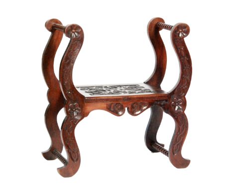 A late 19th Century mahogany stool in the Arts and Crafts style, with bobbin-turned frame and relief carved with foliate and 