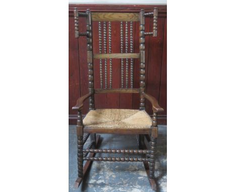Late 19th / early 20th century rush seated oak bobbin decorated rocking chair. Approx. 107cms H x 55cms W 