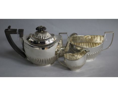 A matched three-piece silver batchelor tea service, of oval half-fluted form, comprising teapot and cream jug, Birmingham 190