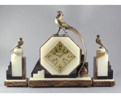 A 1930's onyx and hard stone mantel clock garniture, the octagonal case surmounted by a stylised pheasant, the 6.25 inch Arab